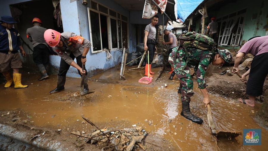 Warga membersihkan sisa-sisa lumpur dan sampah banjir yang melanda Kampung Pensiunan, Desa Tugu Selatan, Kecamatan Cisarua, Kabupaten Bogor, Jawa Barat, Senin (3/3/2025). (CNBC Indonesia/Tri Susilo)