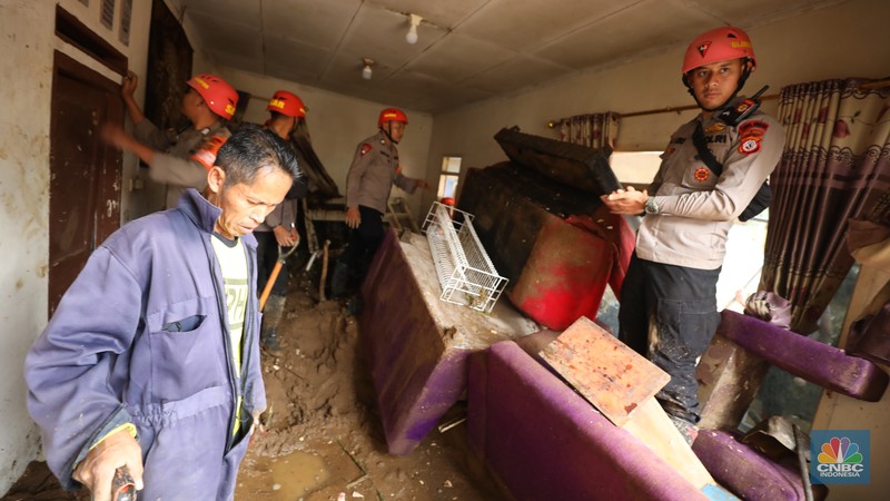 Warga membersihkan sisa-sisa lumpur dan sampah banjir yang melanda Kampung Pensiunan, Desa Tugu Selatan, Kecamatan Cisarua, Kabupaten Bogor, Jawa Barat, Senin (3/3/2025). (CNBC Indonesia/Tri Susilo)