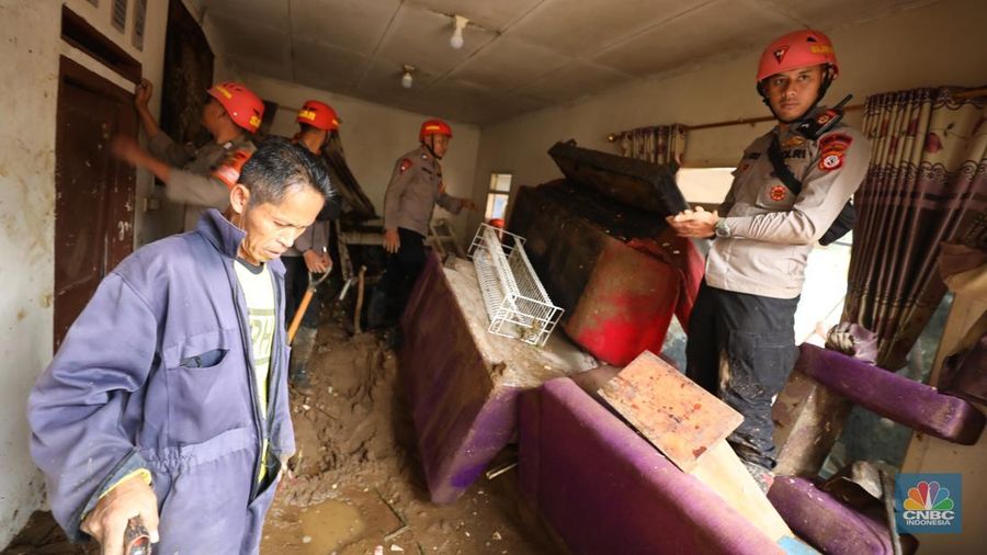 Warga membersihkan sisa-sisa lumpur dan sampah banjir yang melanda Kampung Pensiunan, Desa Tugu Selatan, Kecamatan Cisarua, Kabupaten Bogor, Jawa Barat, Senin (3/3/2025). (CNBC Indonesia/Tri Susilo)