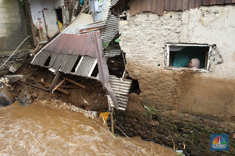 Warga membersihkan sisa-sisa lumpur dan sampah banjir yang melanda Kampung Pensiunan, Desa Tugu Selatan, Kecamatan Cisarua, Kabupaten Bogor, Jawa Barat, Senin (3/3/2025). (CNBC Indonesia/Tri Susilo)