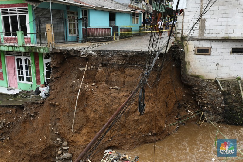 Warga membersihkan sisa-sisa lumpur dan sampah banjir yang melanda Kampung Pensiunan, Desa Tugu Selatan, Kecamatan Cisarua, Kabupaten Bogor, Jawa Barat, Senin (3/3/2025). (CNBC Indonesia/Tri Susilo)