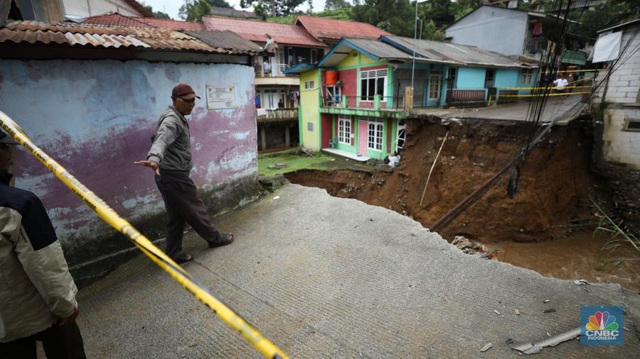 Warga membersihkan sisa-sisa lumpur dan sampah banjir yang melanda Kampung Pensiunan, Desa Tugu Selatan, Kecamatan Cisarua, Kabupaten Bogor, Jawa Barat, Senin (3/3/2025). (CNBC Indonesia/Tri Susilo)