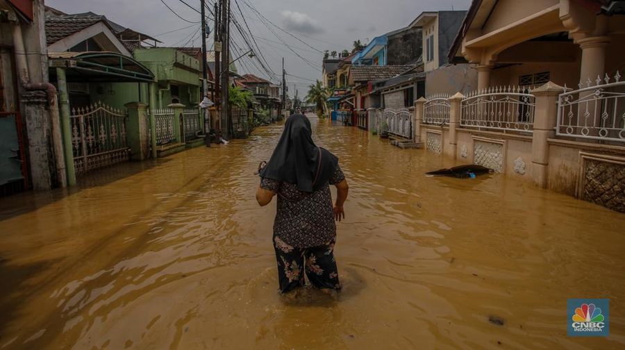 Warga melintasi banjir yang melanda Perumahan Villa Nusa Indah 1, Kecamatan Gunung Putri, Kabupaten Bogor, Jawa Barat, Selasa (4/3/2025). (CNBC Indonesia/Faisal Rahman)