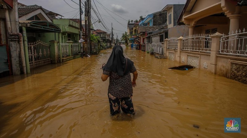 Warga melintasi banjir yang melanda Perumahan Villa Nusa Indah 1, Kecamatan Gunung Putri, Kabupaten Bogor, Jawa Barat, Selasa (4/3/2025). (վ/Faisal Rahman)