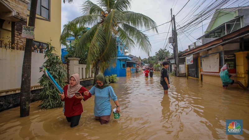 Warga melintasi banjir yang melanda Perumahan Villa Nusa Indah 1, Kecamatan Gunung Putri, Kabupaten Bogor, Jawa Barat, Selasa (4/3/2025). (վ/Faisal Rahman)