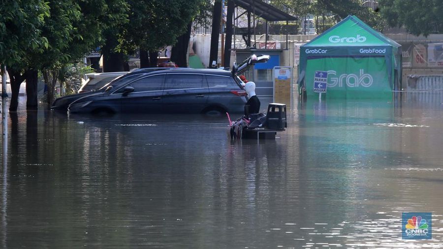 Sejumlah karyawan kios toko mengevakuasi sejumlah pakaian yang terendam banjir di halaman luar lantai bawah mall Hypermall Bekasi, Jawa Barat, Rabu 5/3. (CNBC Indonesia/Muhammad Sabki)