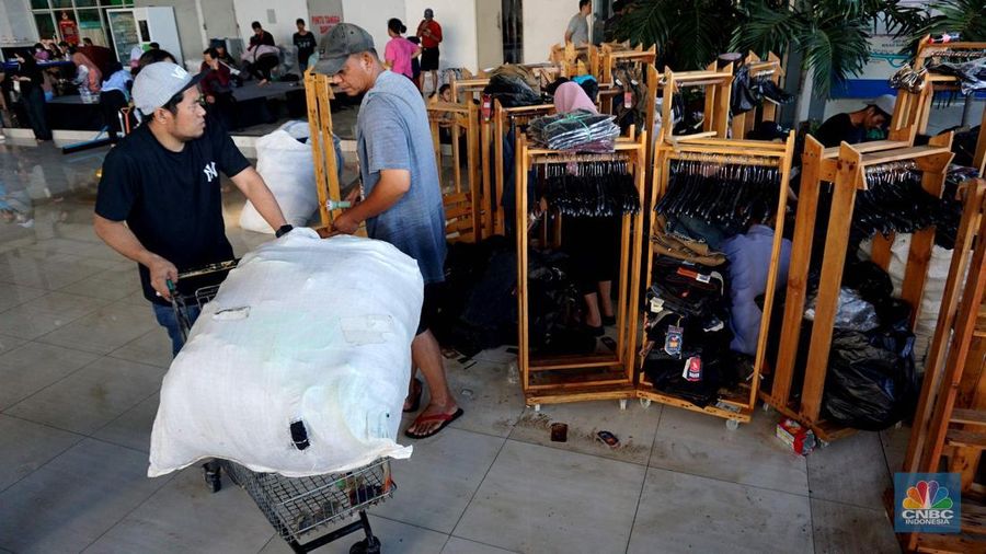 Sejumlah karyawan kios toko mengevakuasi sejumlah pakaian yang terendam banjir di halaman luar lantai bawah mall Hypermall Bekasi, Jawa Barat, Rabu 5/3. (CNBC Indonesia/Muhammad Sabki)