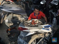 Seorang montir memperbaiki motor yang rusak terendam banjir di kawasan Bekasi, Jawa Barat, Rabu (5/3/2025). (CNBC Indonesia/Muhammad Sabki)