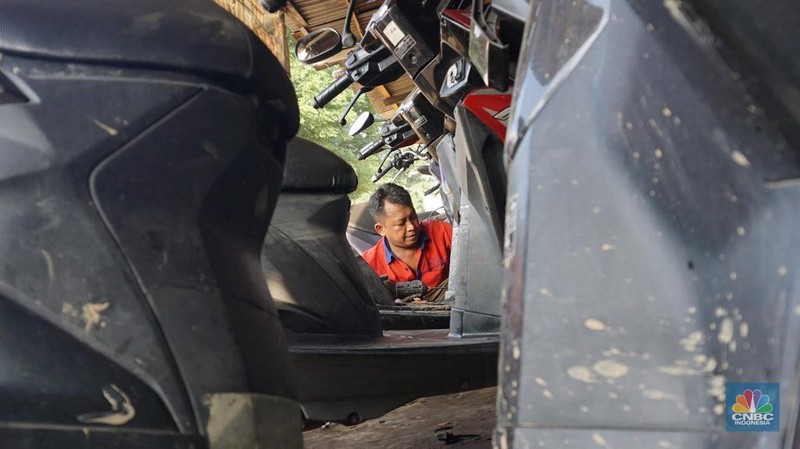 Seorang montir memperbaiki motor yang rusak terendam banjir di kawasan Bekasi, Jawa Barat, Rabu (5/3/2025). (վ/Muhammad Sabki)