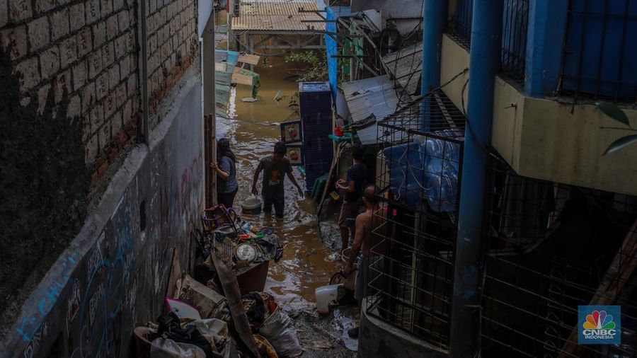 Warga melintasi banjir yang melanda pemukiman padat di Kelurahan Pengadegan, Pancoran, Jakarta, Rabu (5/3/2025). (CNBC Indonesia/Faisal Rahman)