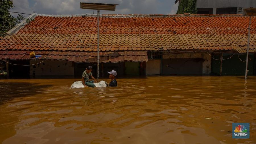 Warga melintasi banjir yang melanda pemukiman padat di Kelurahan Pengadegan, Pancoran, Jakarta, Rabu (5/3/2025). (CNBC Indonesia/Faisal Rahman)