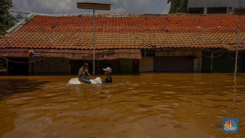 Warga melintasi banjir yang melanda pemukiman padat di Kelurahan Pengadegan, Pancoran, Jakarta, Rabu (5/3/2025). (վ/Faisal Rahman)