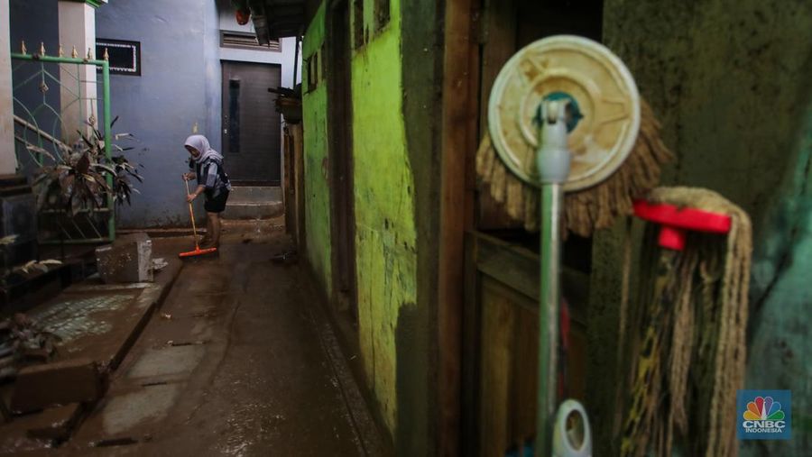 Warga membersihkan lumpur sisa endapan banjir di kawasan Rawajati, Jakarta, Rabu (5/3/2025). (CNBC Indonesia/Faisal Rahman)