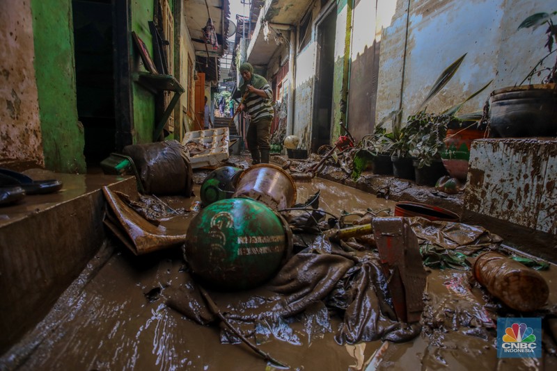 Warga membersihkan lumpur sisa endapan banjir di kawasan Rawajati, Jakarta, Rabu (5/3/2025). (CNBC Indonesia/Faisal Rahman)