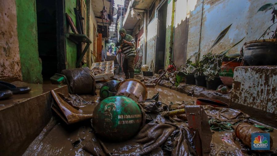 Warga membersihkan lumpur sisa endapan banjir di kawasan Rawajati, Jakarta, Rabu (5/3/2025). (CNBC Indonesia/Faisal Rahman)