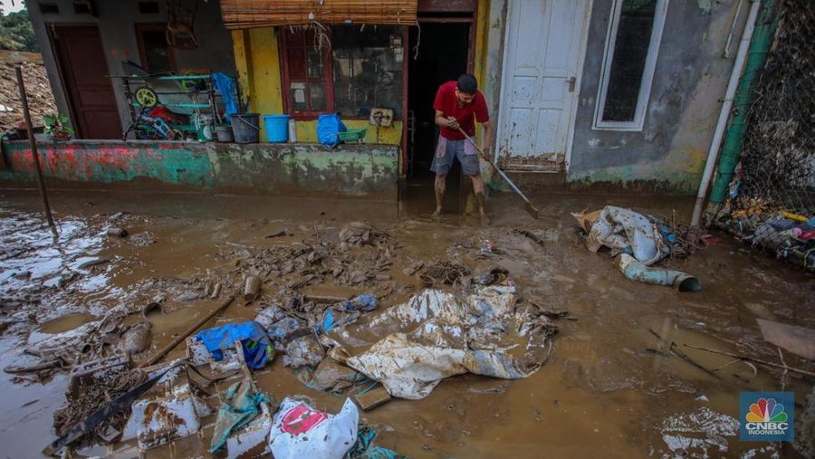 Warga membersihkan lumpur sisa endapan banjir di kawasan Rawajati, Jakarta, Rabu (5/3/2025). (CNBC Indonesia/Faisal Rahman)