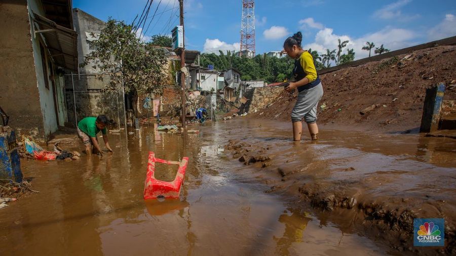 Warga membersihkan lumpur sisa endapan banjir di kawasan Rawajati, Jakarta, Rabu (5/3/2025). (CNBC Indonesia/Faisal Rahman)