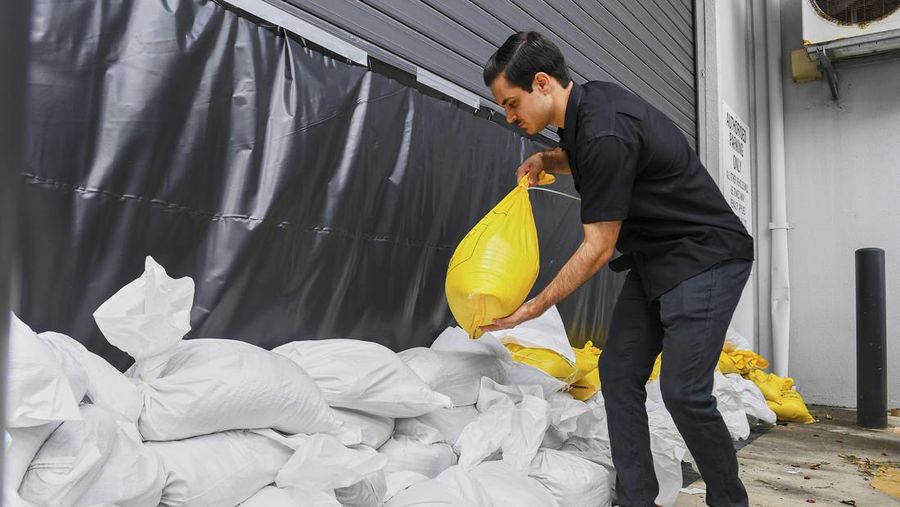 Warga mengumpulkan karung pasir di sebuah depot di Pulau Bribie, Queensland, Selasa, 4 Maret 2025, saat mereka bersiap menghadapi Siklon Alfred yang mendekat. (Jono Searle/AAP Image via AP)