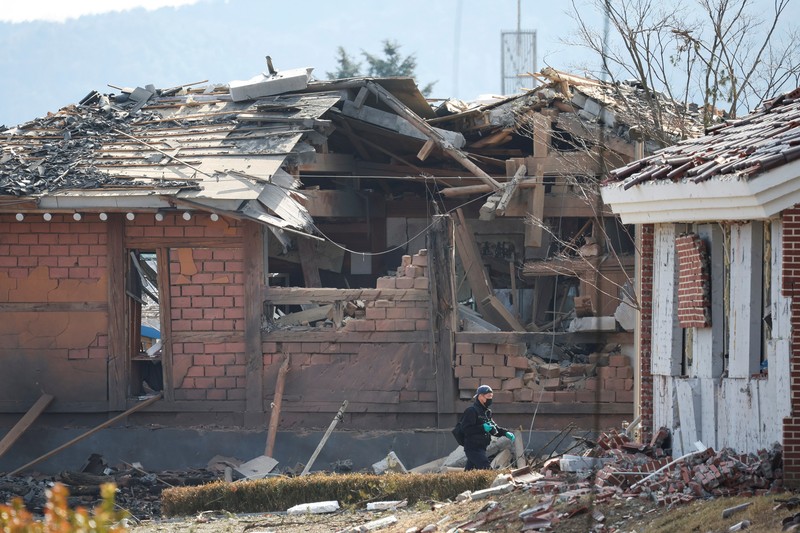 Officials stand near damaged buildings after South Korea's Air Force said that Mk82 bombs fell from a KF-16 jet outside the shooting range during joint live-fire exercises near the demilitarized zone separating two Koreas in Pocheon, South Korea, March 6, 2025. REUTERS/Kim Hong-Ji