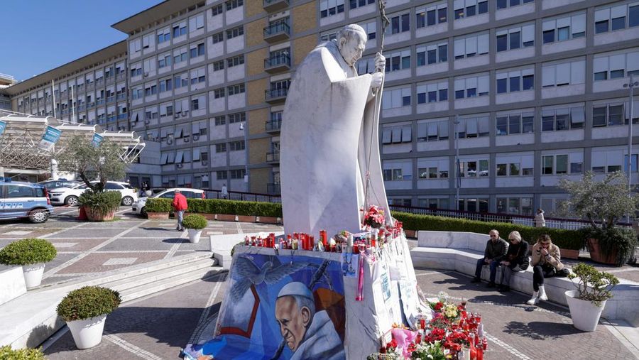 Orang-orang berdoa di dekat patung mendiang Paus Yohanes Paulus II di luar Rumah Sakit Gemelli tempat Paus Fransiskus dirawat, di Roma, Italia, 5 Maret 2025. (REUTERS/Remo Casilli)