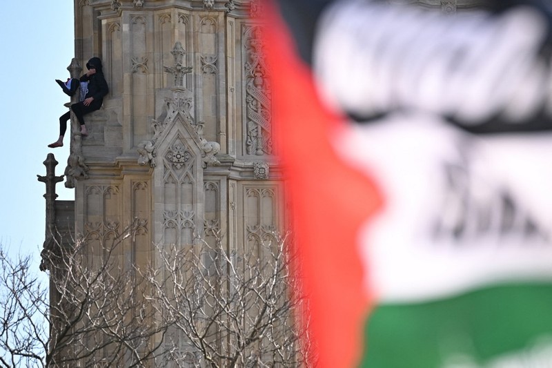 Seorang pengunjuk rasa memanjat Menara Elizabeth  atau yang dikenal sebagai Big Ben di London, Inggris, Sabtu (8/3/2025). (Ben STANSALL / AFP)