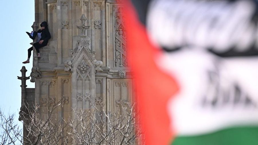 Seorang pengunjuk rasa memanjat Menara Elizabeth  atau yang dikenal sebagai Big Ben di London, Inggris, Sabtu (8/3/2025). (Ben STANSALL / AFP)