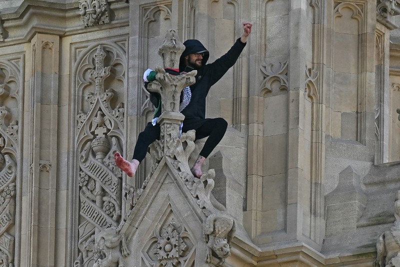 Seorang pengunjuk rasa memanjat Menara Elizabeth  atau yang dikenal sebagai Big Ben di London, Inggris, Sabtu (8/3/2025). (Ben STANSALL / AFP)
