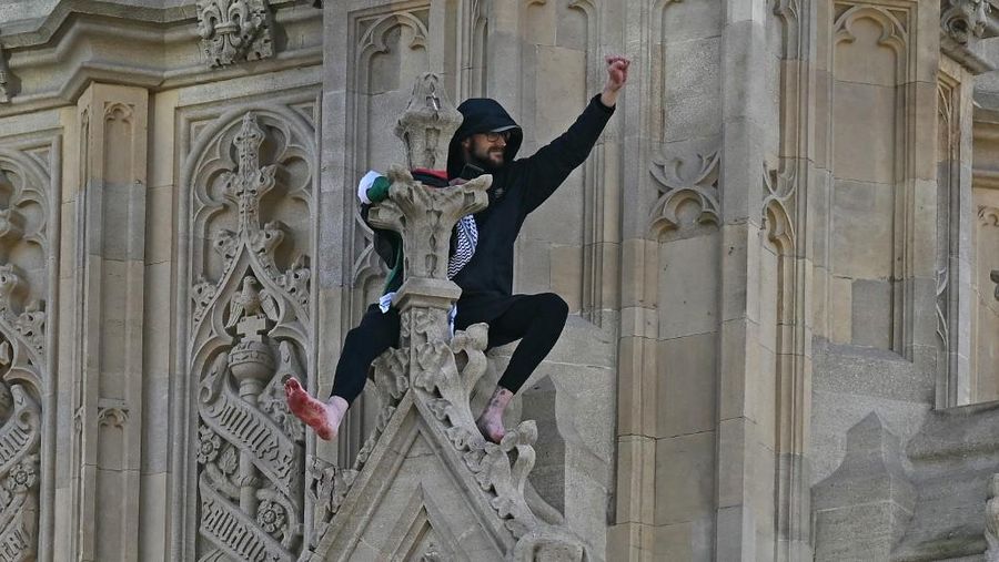 Seorang pengunjuk rasa memanjat Menara Elizabeth  atau yang dikenal sebagai Big Ben di London, Inggris, Sabtu (8/3/2025). (Ben STANSALL / AFP)