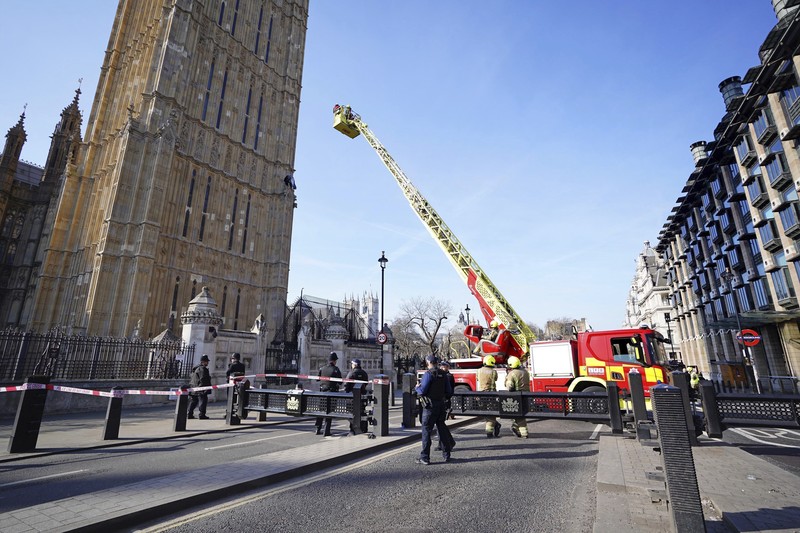 Seorang pengunjuk rasa memanjat Menara Elizabeth  atau yang dikenal sebagai Big Ben di London, Inggris, Sabtu (8/3/2025). (Ben STANSALL / AFP)