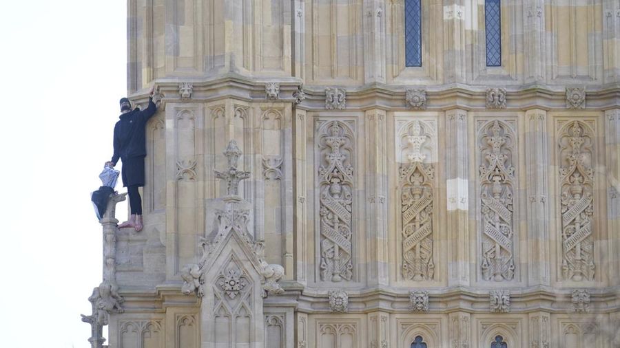 Seorang pengunjuk rasa memanjat Menara Elizabeth  atau yang dikenal sebagai Big Ben di London, Inggris, Sabtu (8/3/2025). (Ben STANSALL / AFP)