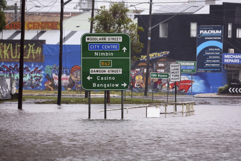 Warga Bruce Maddox berjalan kembali melewati banjir menuju rumahnya di pinggiran kota Brisbane, Oxley, Australia, Senin, 10 Maret 2025. (Jono Searle/AAP Image via AP)