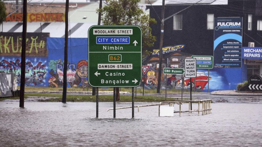 Warga Bruce Maddox berjalan kembali melewati banjir menuju rumahnya di pinggiran kota Brisbane, Oxley, Australia, Senin, 10 Maret 2025. (Jono Searle/AAP Image via AP)