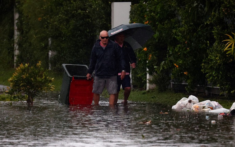 Warga Bruce Maddox berjalan kembali melewati banjir menuju rumahnya di pinggiran kota Brisbane, Oxley, Australia, Senin, 10 Maret 2025. (Jono Searle/AAP Image via AP)