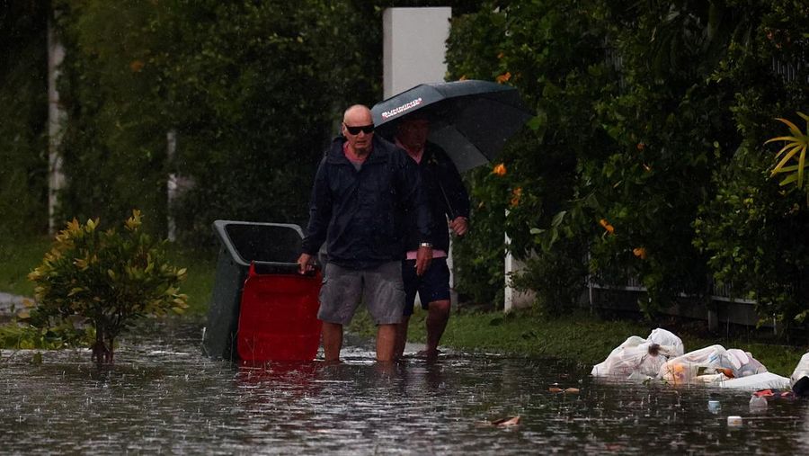 Warga Bruce Maddox berjalan kembali melewati banjir menuju rumahnya di pinggiran kota Brisbane, Oxley, Australia, Senin, 10 Maret 2025. (Jono Searle/AAP Image via AP)