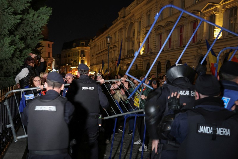 Pendukung kandidat sayap kanan Calin Georgescu berhadapan dengan polisi anti huru hara di luar biro pemilihan pusat Rumania, setelah penolakan pencalonannya untuk pemilihan ulang presiden pada bulan Mei, di Bukares, Rumania, 9 Maret 2025. Pendukung kandidat sayap kanan Calin Georgescu berhadapan dengan polisi anti huru hara di luar biro pemilihan pusat Rumania, setelah penolakan pencalonannya untuk pemilihan ulang presiden pada bulan Mei, di Bukares, Rumania, 9 Maret 2025. (Inquam Photos/George Calin via REUTERS)