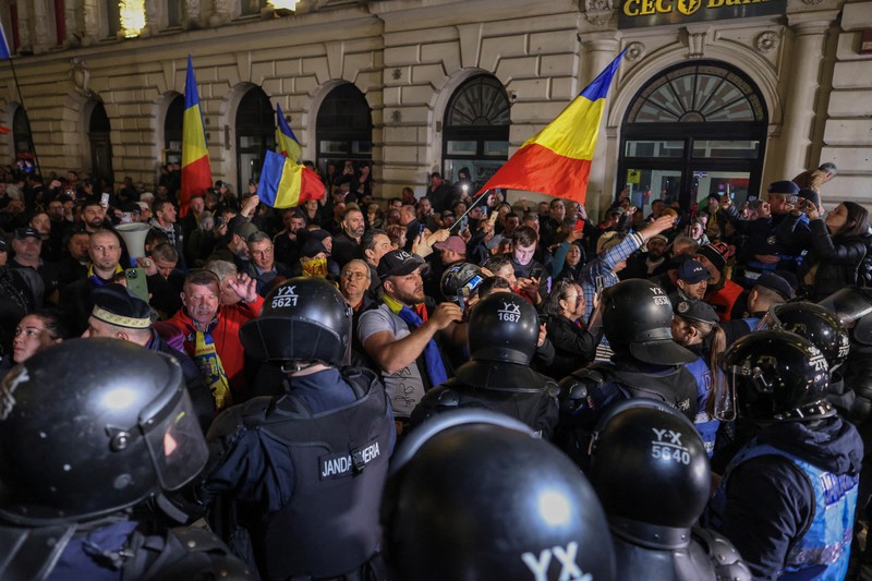 Pendukung kandidat sayap kanan Calin Georgescu berhadapan dengan polisi anti huru hara di luar biro pemilihan pusat Rumania, setelah penolakan pencalonannya untuk pemilihan ulang presiden pada bulan Mei, di Bukares, Rumania, 9 Maret 2025. (Inquam Photos/George Calin via REUTERS)