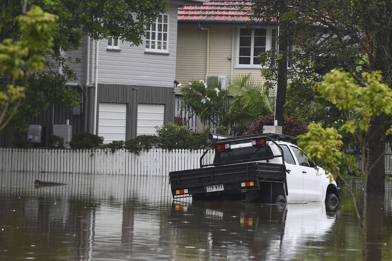 Warga Bruce Maddox berjalan kembali melewati banjir menuju rumahnya di pinggiran kota Brisbane, Oxley, Australia, Senin, 10 Maret 2025. (Jono Searle/AAP Image via AP)