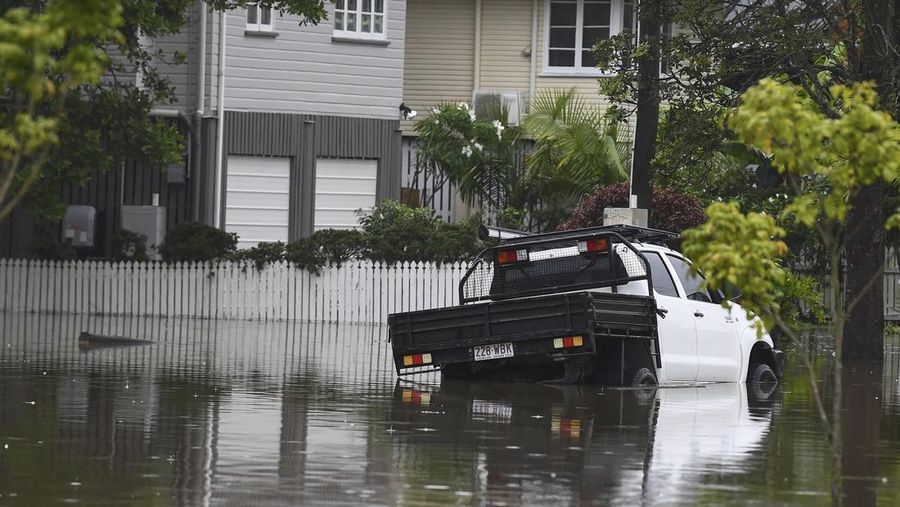 Warga Bruce Maddox berjalan kembali melewati banjir menuju rumahnya di pinggiran kota Brisbane, Oxley, Australia, Senin, 10 Maret 2025. (Jono Searle/AAP Image via AP)