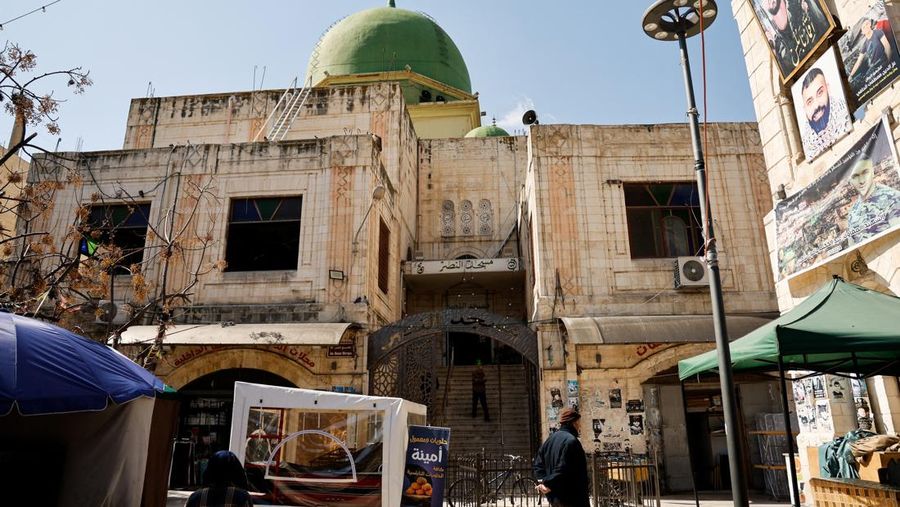 Seorang pria Palestina berdiri di pintu masuk masjid sehari setelah tentara Israel membakar masjid Al-Nasser di Nablus, di tengah serangan Tepi Barat, 8 Maret 2025. (REUTERS/Raneen Sawafta)