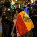 Seorang wanita tua yang terbungkus bendera era Komunis Rumania berbicara kepada polisi antihuru-hara yang memblokir jalan menyusul bentrokan dengan pendukung Calin Georgescu setelah badan pemilihan Rumania menolak pencalonannya dalam pemilihan ulang