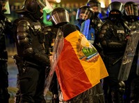 Seorang wanita tua yang terbungkus bendera era Komunis Rumania berbicara kepada polisi antihuru-hara yang memblokir jalan menyusul bentrokan dengan pendukung Calin Georgescu setelah badan pemilihan Rumania menolak pencalonannya dalam pemilihan ulang