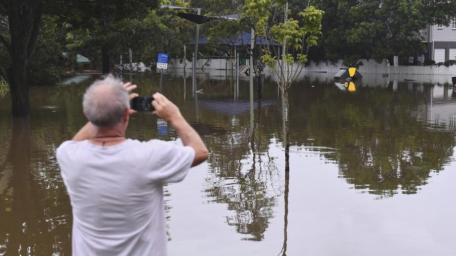 Warga Bruce Maddox berjalan kembali melewati banjir menuju rumahnya di pinggiran kota Brisbane, Oxley, Australia, Senin, 10 Maret 2025. (Jono Searle/AAP Image via AP)