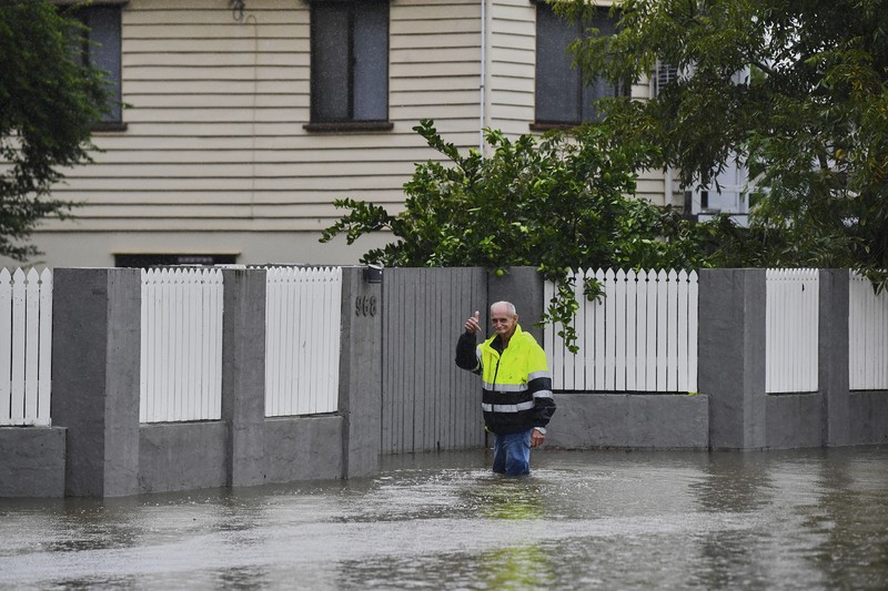 Warga Bruce Maddox berjalan kembali melewati banjir menuju rumahnya di pinggiran kota Brisbane, Oxley, Australia, Senin, 10 Maret 2025. (Jono Searle/AAP Image via AP)