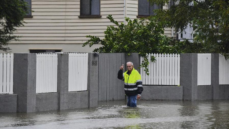 Warga Bruce Maddox berjalan kembali melewati banjir menuju rumahnya di pinggiran kota Brisbane, Oxley, Australia, Senin, 10 Maret 2025. (Jono Searle/AAP Image via AP)