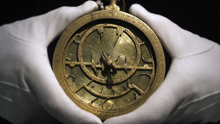 Seorang karyawan Sotheby's memegang Astrolabe yang berasal dari tahun 1020 M sebagai bagian dari lelang Seni Timur Tengah. (AP/Frank Augstein)