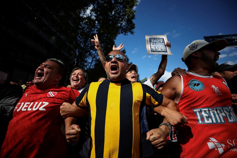 Penggemar sepak bola bergabung dalam protes mingguan para pensiunan terhadap kebijakan penyesuaian Presiden Argentina Javier Milei, oleh Kongres Nasional di Buenos Aires, Argentina 12 Maret 2025. (REUTERS/Agustin Marcarian)