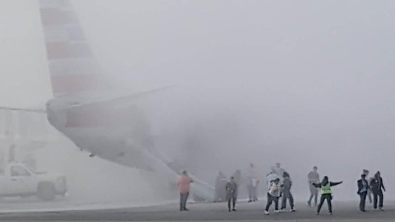 Asap mengepul setelah salah satu mesin pesawat American Airlines terbakar di Bandara Internasional Denver pada Kamis (13/3/2025) malam. (Tangkapan Layar Video AFP/Joshua Sunberg via CBS)