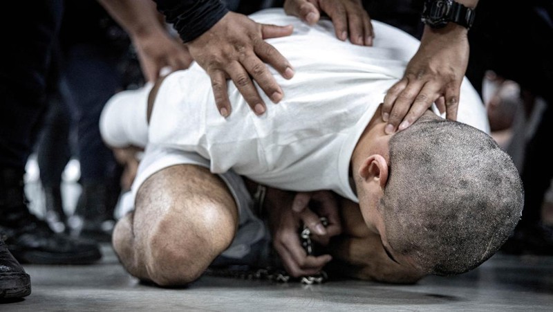 Petugas polisi Salvador mengawal terduga anggota geng Venezuela Tren de Aragua yang baru-baru ini dideportasi oleh pemerintah AS untuk dipenjara di penjara Pusat Penahanan Terorisme (CECOT), sebagai bagian dari perjanjian dengan pemerintah Salvador, di Tecoluca, El Salvador, dalam gambar selebaran ini yang diperoleh pada tanggal 16 Maret 2025. (Secretaria de Prensa de la Presidencia/Handout via REUTERS)