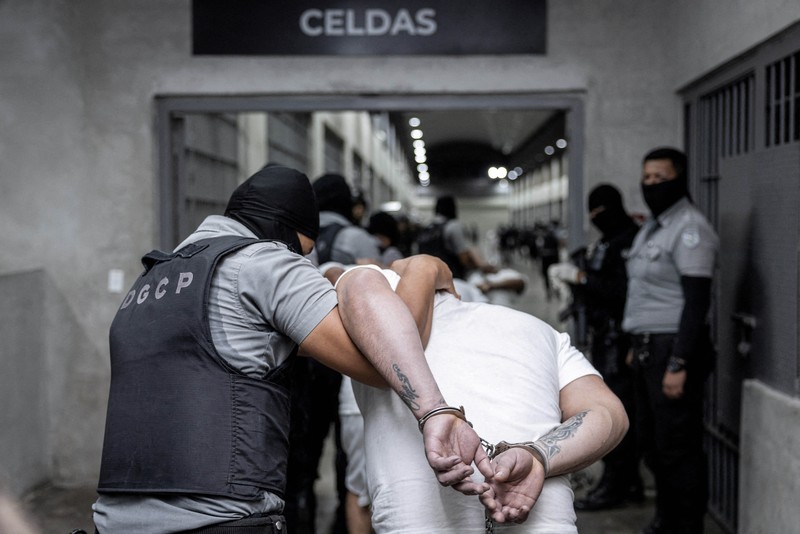 Petugas polisi Salvador mengawal terduga anggota geng Venezuela Tren de Aragua yang baru-baru ini dideportasi oleh pemerintah AS untuk dipenjara di penjara Pusat Penahanan Terorisme (CECOT), sebagai bagian dari perjanjian dengan pemerintah Salvador, di Tecoluca, El Salvador, dalam gambar selebaran ini yang diperoleh pada tanggal 16 Maret 2025. (Secretaria de Prensa de la Presidencia/Handout via REUTERS)