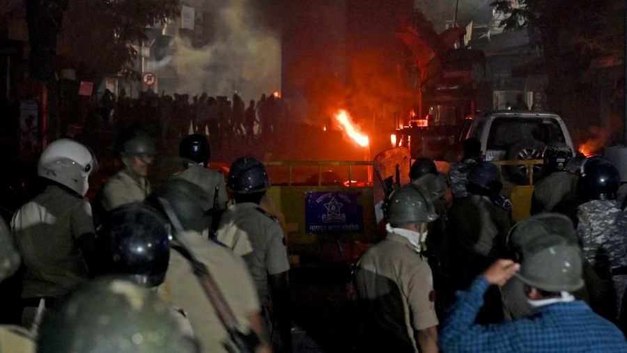 Seorang petugas pemadam kebakaran berdiri di dekat kendaraan yang terbakar setelah bentrokan di kawasan Chitnavis Park Square, Nagpur pada 17 Maret 2025. (AFP)